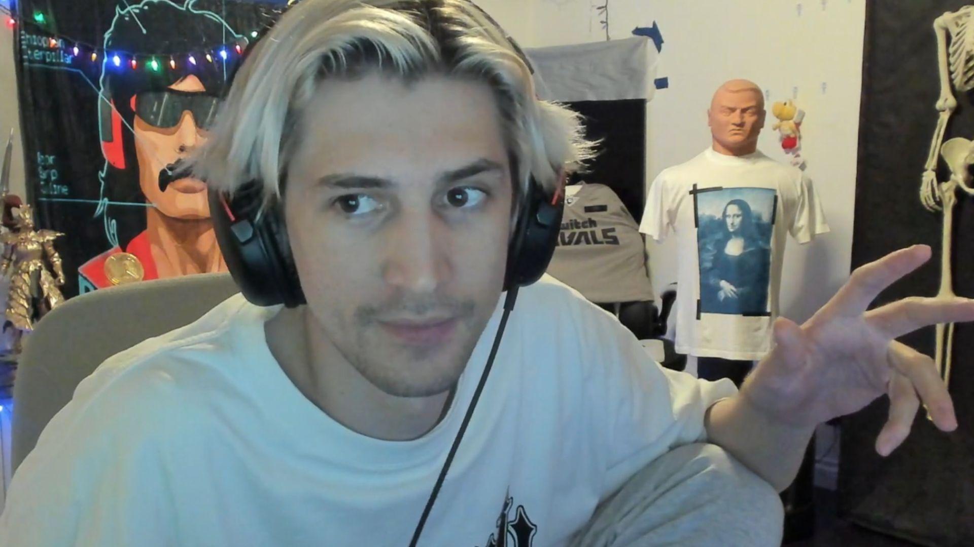 xQc in white shirt talking to camera with hand raised