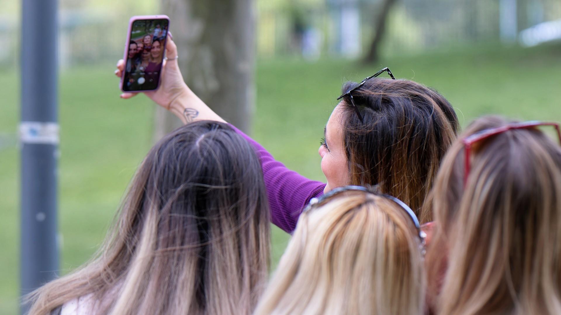 A group of women trying to capture a selfie on a smartphone