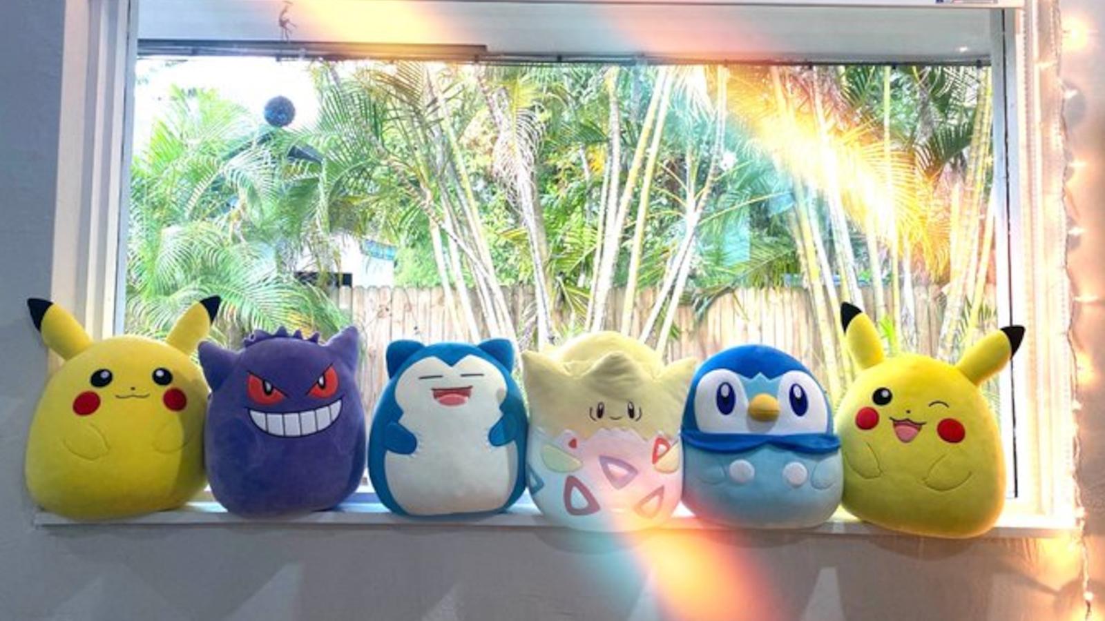 All Squishmallows Pokemon crossover plushies arranged on a window sill.