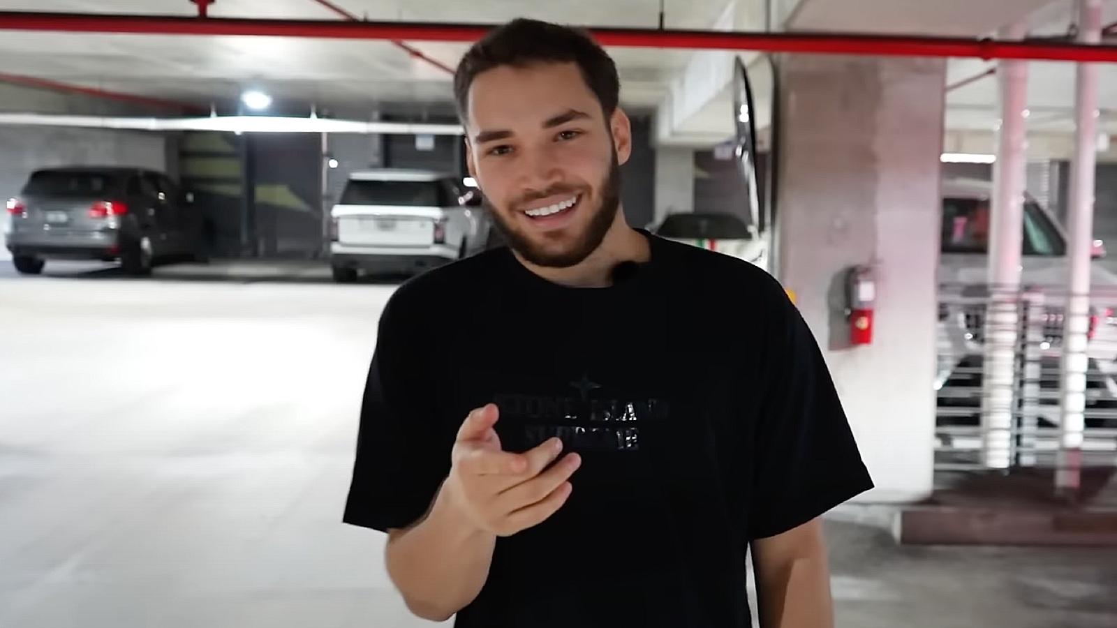 Adin Ross pointing at camera and smiling in parking lot