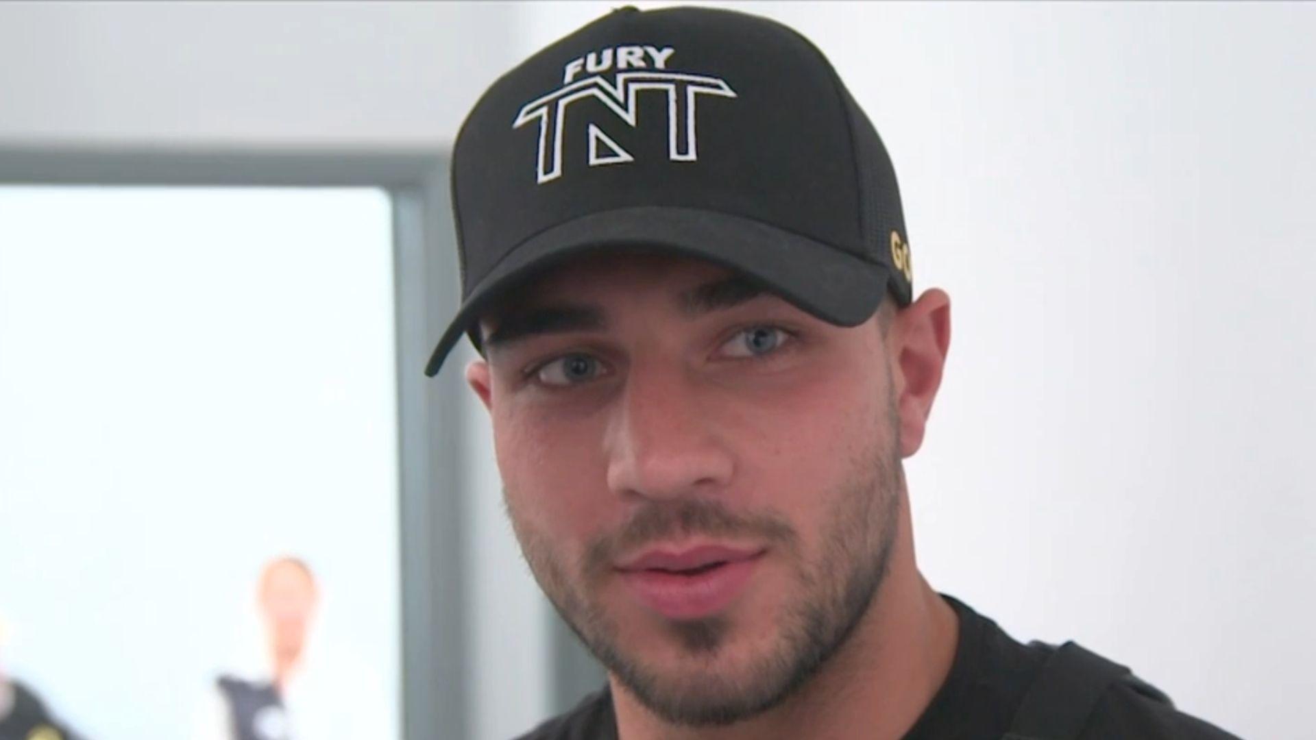 Tommy Fury in black and white hat talking into microphone