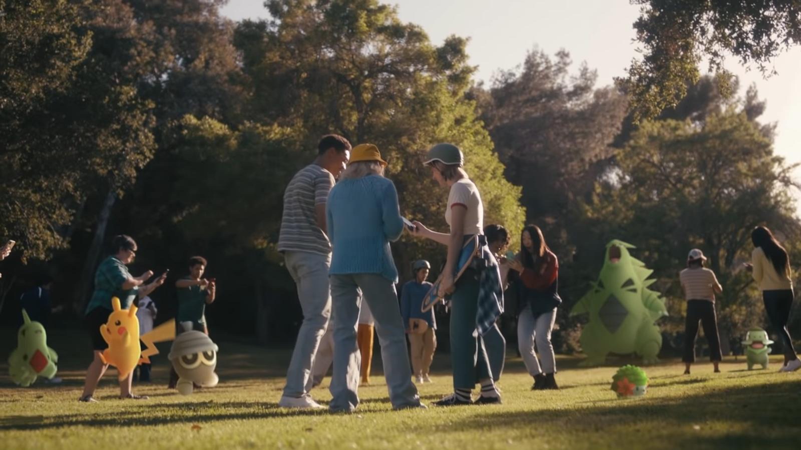 Pokemon Go players playing in a field next to numerous Pokemon.