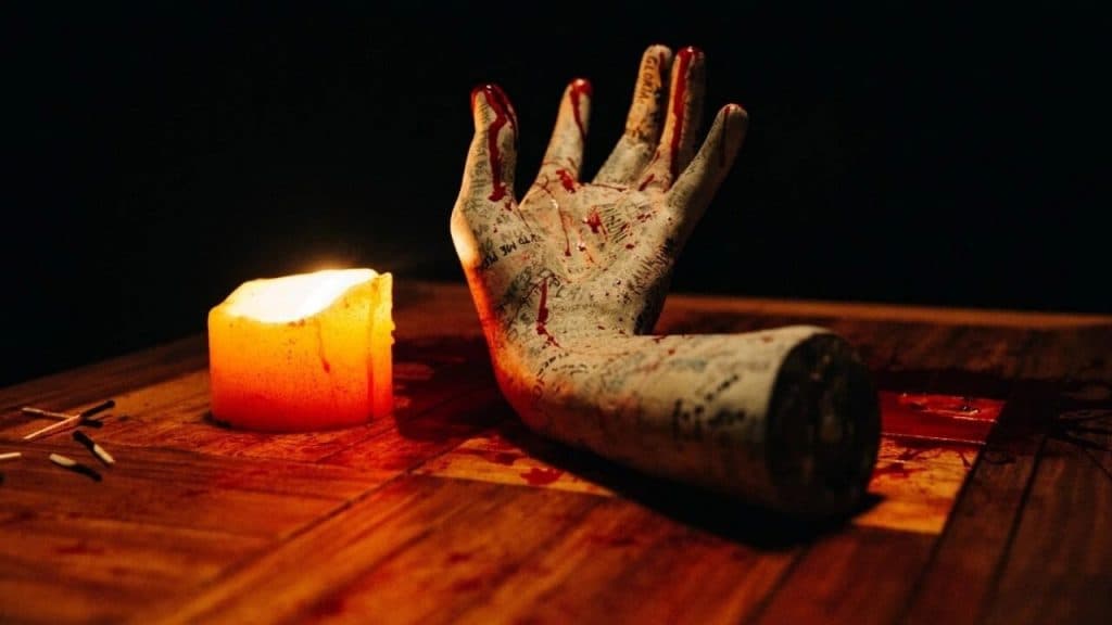 An embalmed hand and candle from the film Talk to Me.