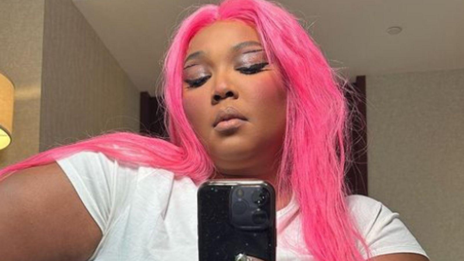 lizzo taking picture with pink hair and a white tshirt