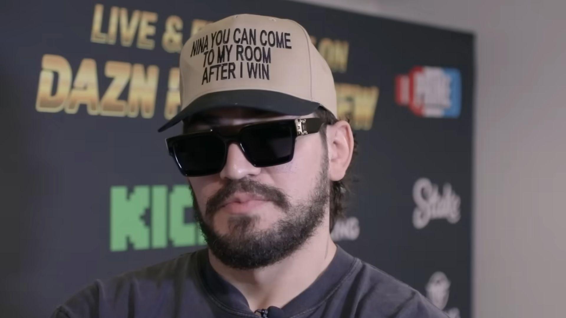 Dillon Danis in hat and glasses talking to camera