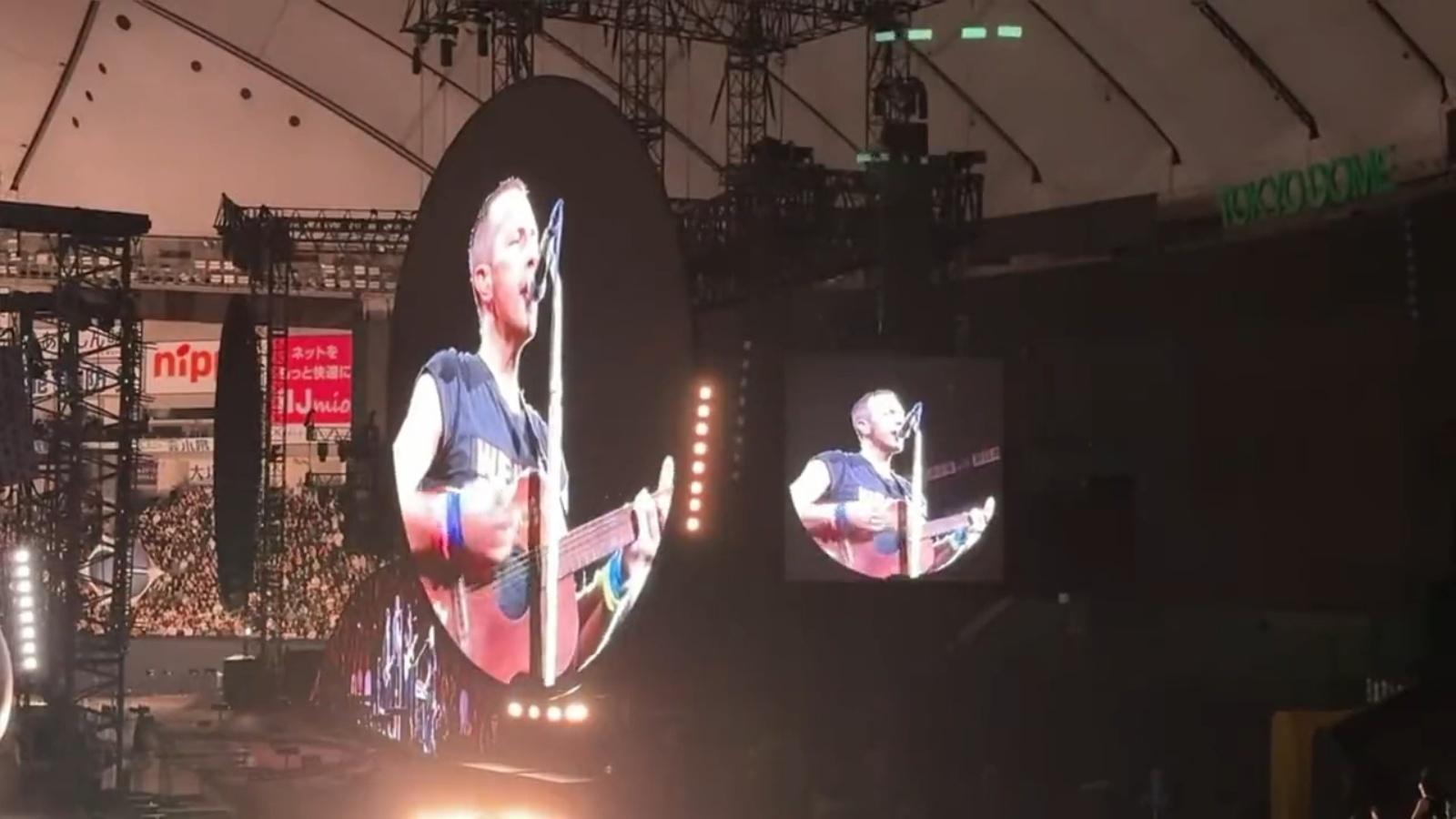 Coldplay lead singer Chris Martin performs with an acoustic guitar on stage at the Tokyo Dome stadium.