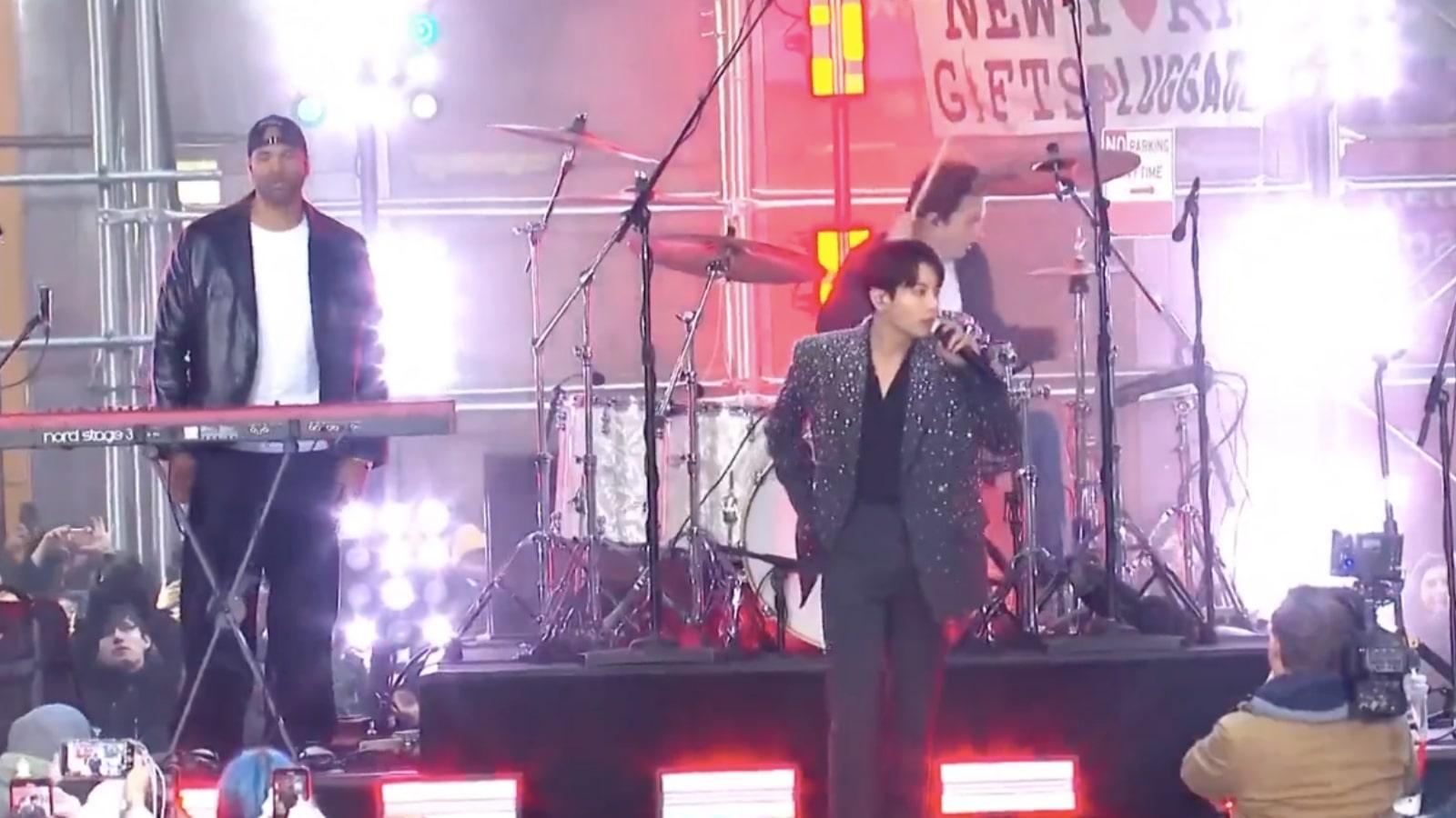 Jungkook in a sparkling jacket performs onstage during a concert.