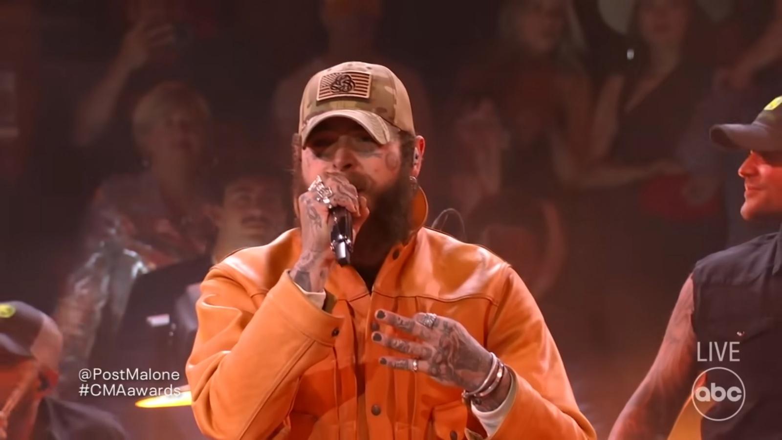 Post Malone performs in an orange outfit at the CMA Awards
