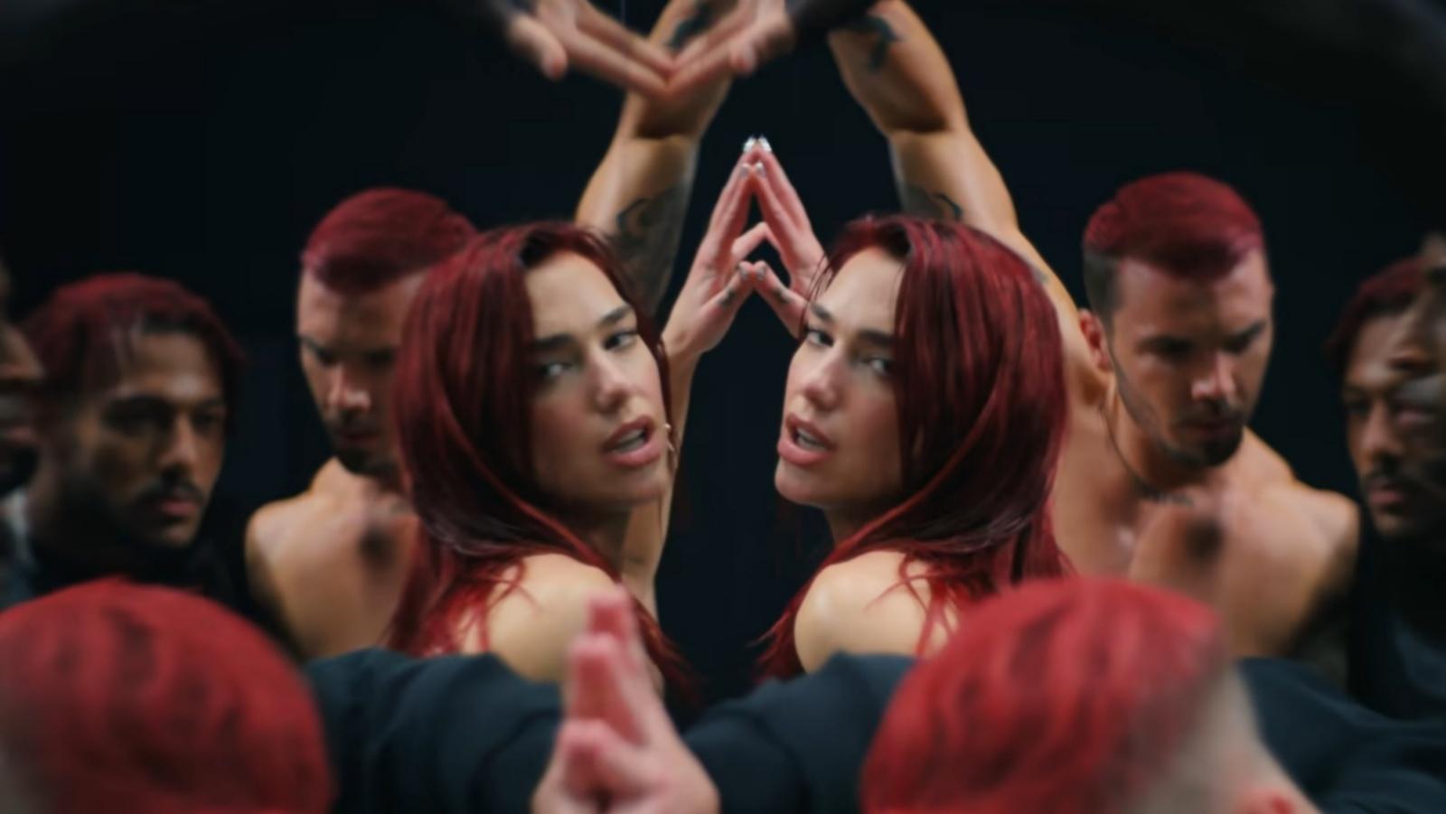 Dua Lipa with red hair poses in front of a mirror