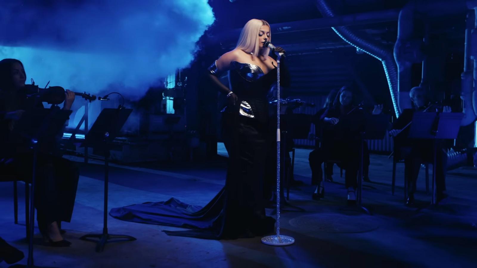 Bebe Rexha in an elegant black gown performing onstage in an award show