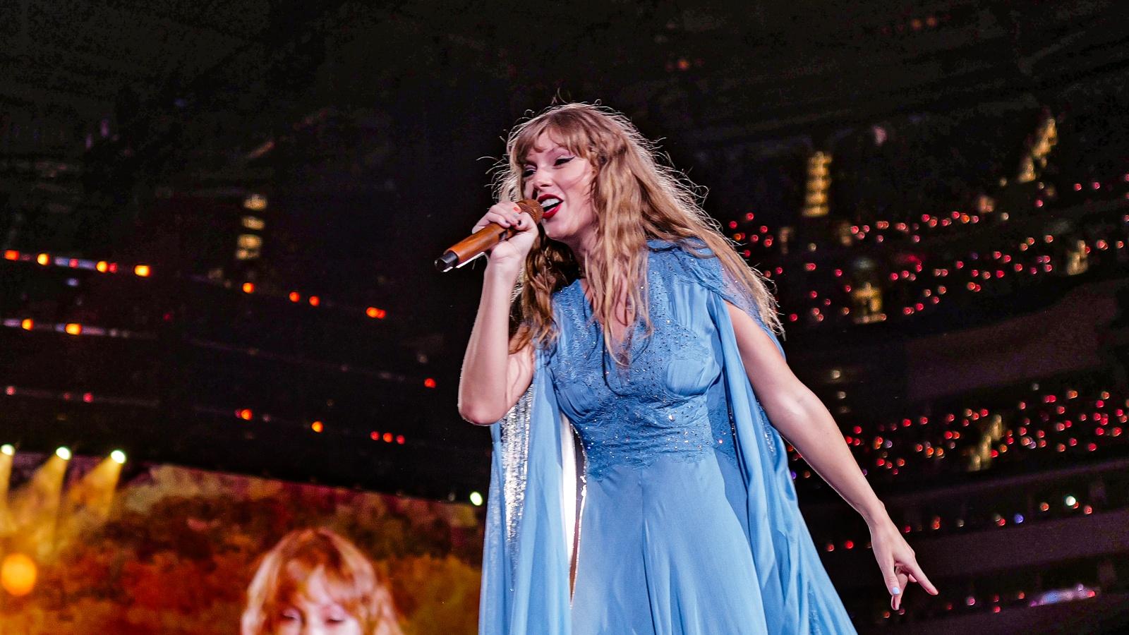 Taylor Swift performing in a sparkling blue dress onstage in a concert