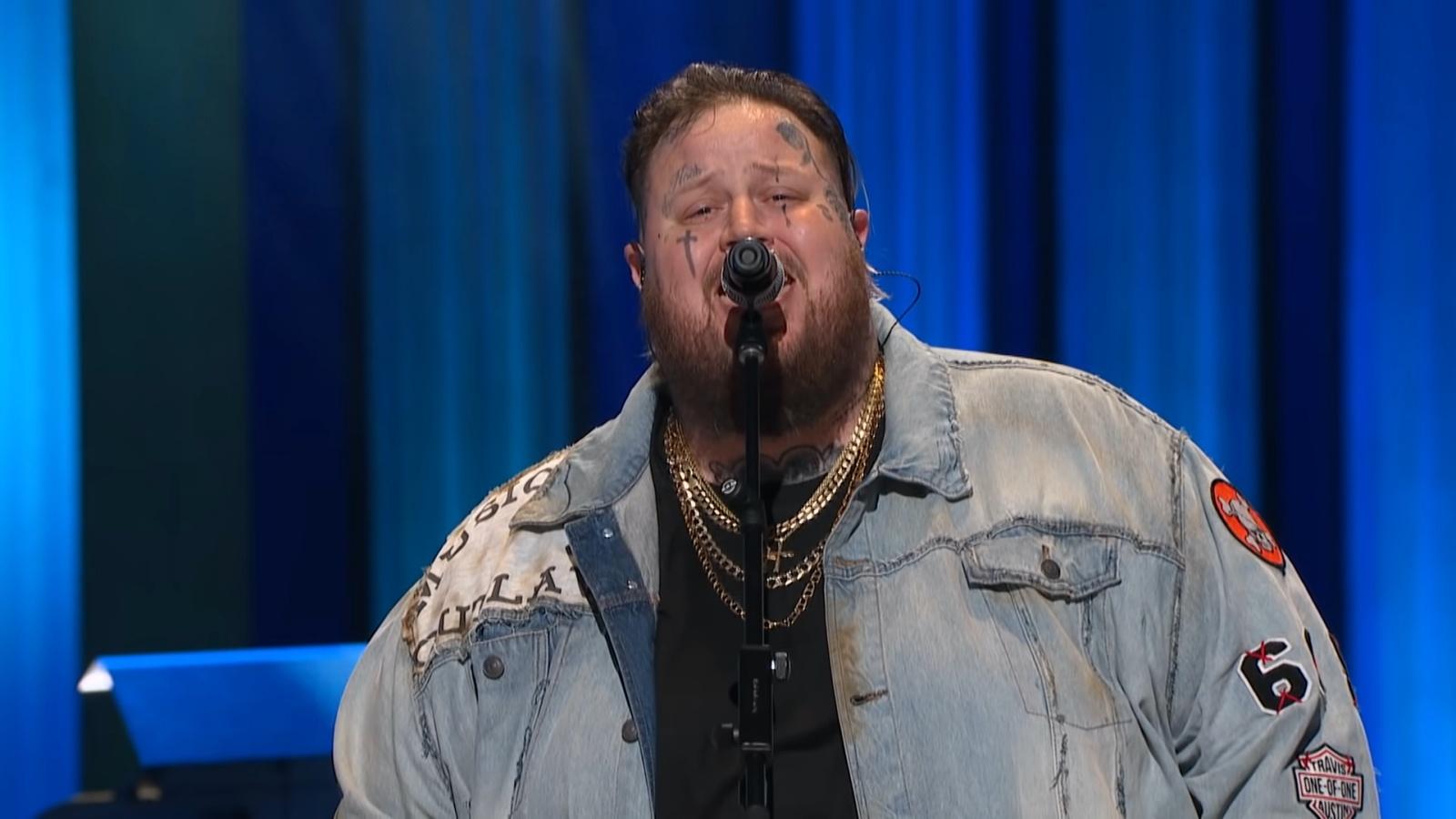 Jelly Roll performing behind a microphone onstage at the Opry