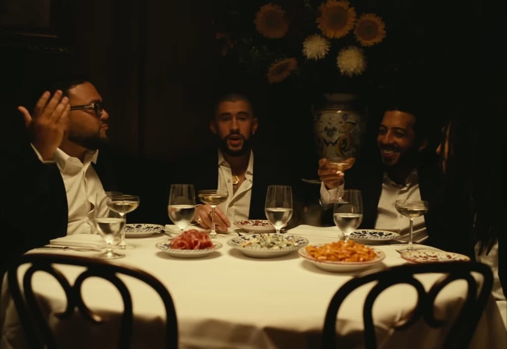 Bad Bunny sitting at a dinner table surrounded by other people