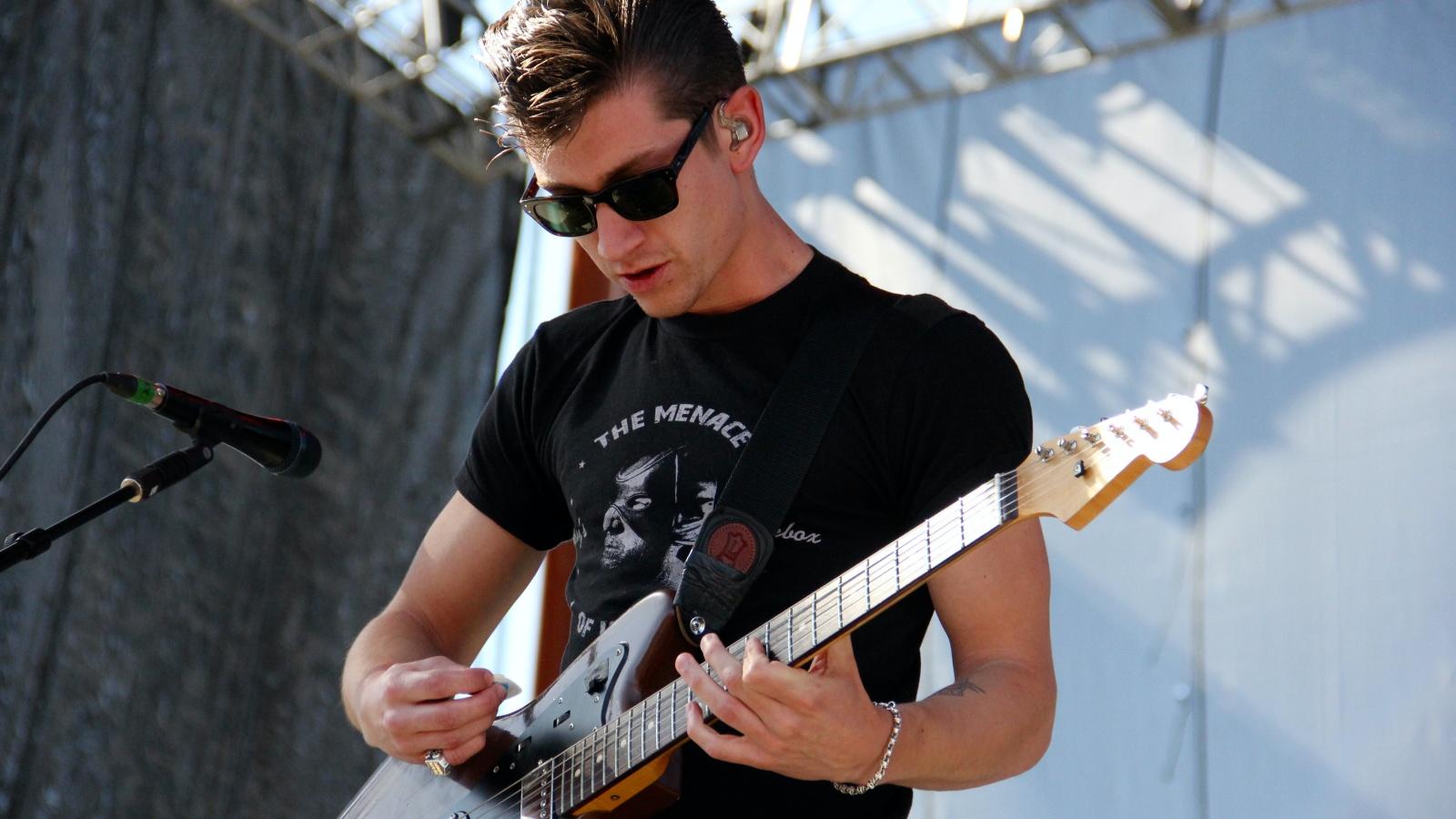 Arctic Monkeys' Alex Turner performing with an electric guitar onstage at a concert
