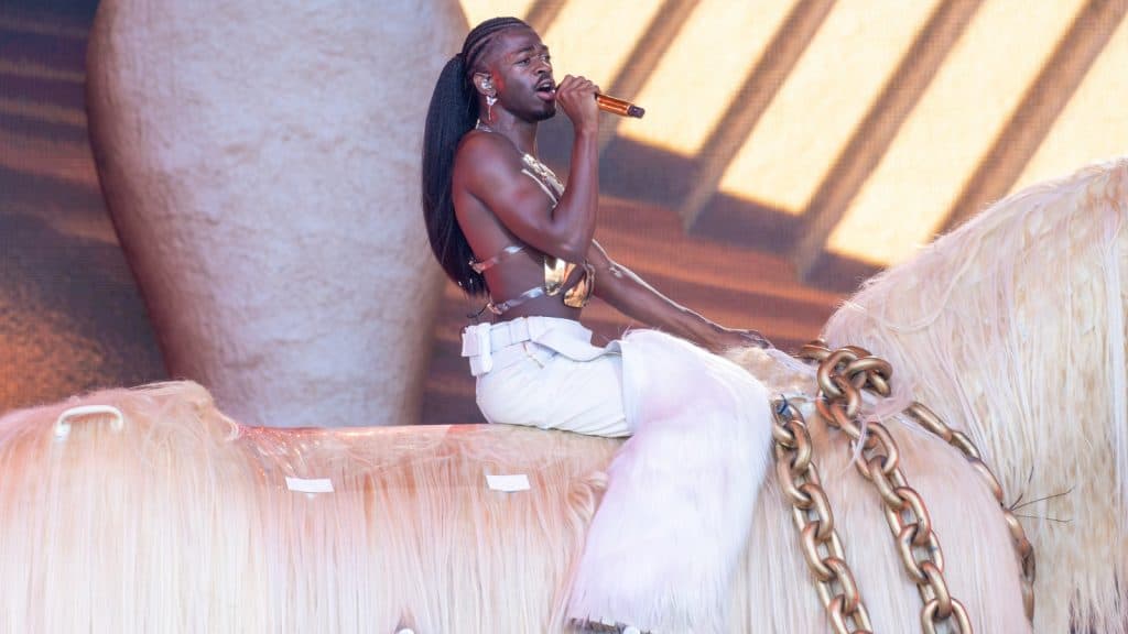 Lil Nas X sitting on a horse performing onstage at a concert