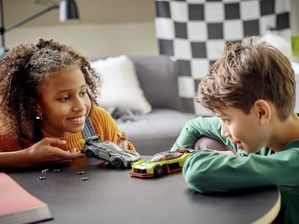 Two children playing with the LEGO-reimagined Aston Martin Valkyrie AMR Pro and Vantage GT3.