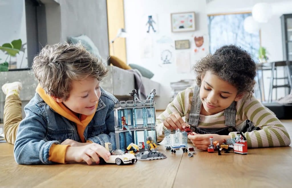 Two children playing with the LEGO Marvel Iron Man's Armory set.
