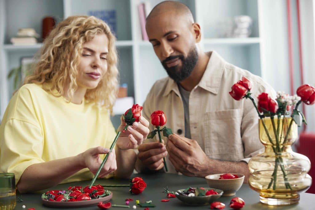 Two adults building the the LEGO-reimagined long-stem roses.