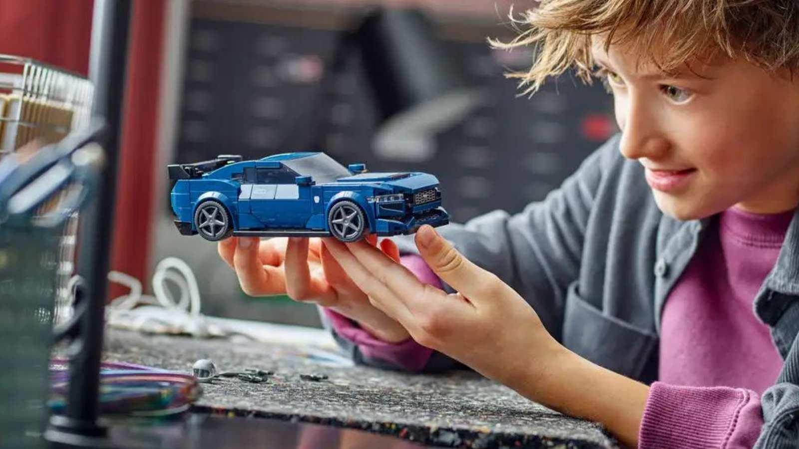 A child with their LEGO Speed Champions Ford Mustang Dark Horse set.