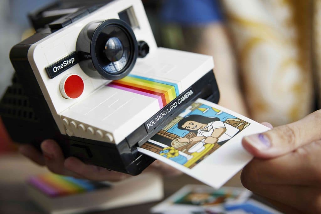 A LEGO Builder takes out one of the illustrated photos included with the LEGO Ideas Polaroid Camera set.