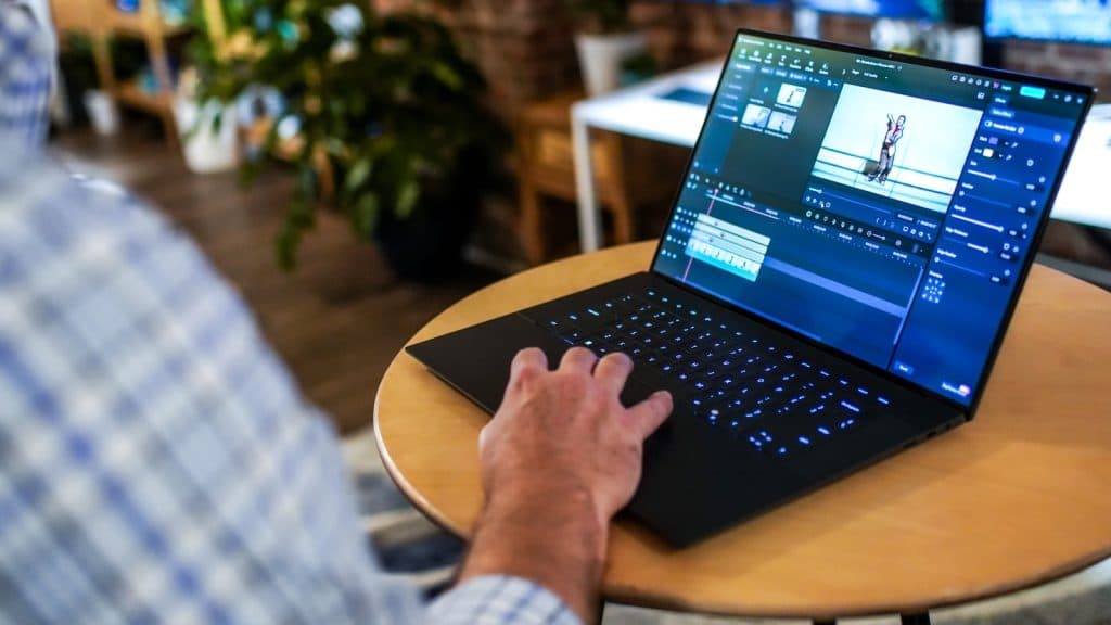 Dell XPS 16 being used on a desk with someone holding the touchpad