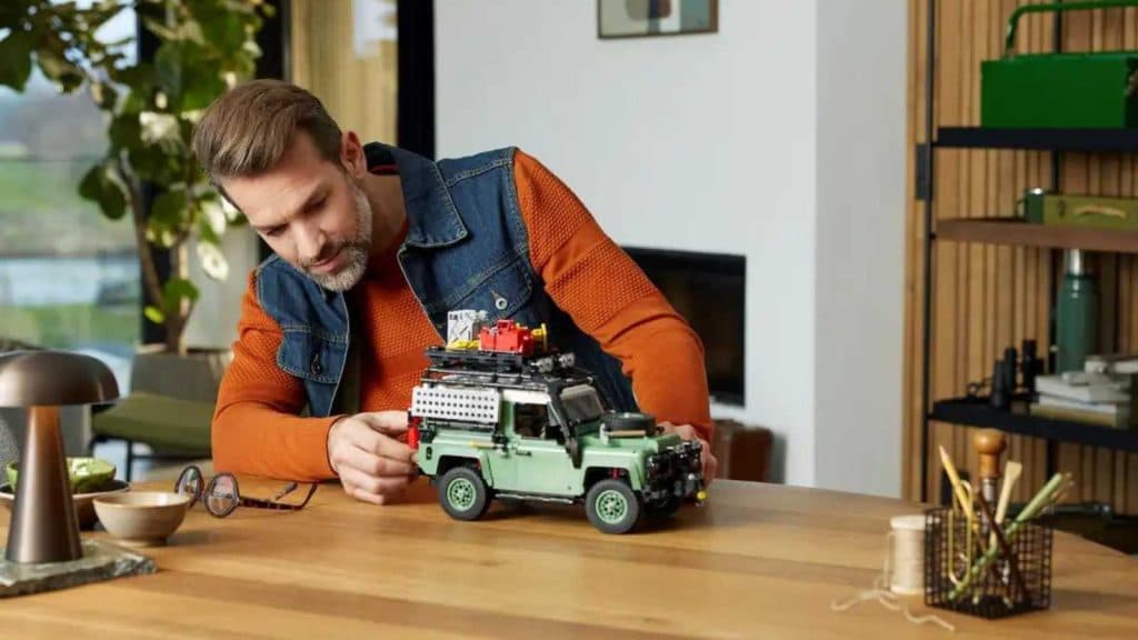 An adult admiring their LEGO Icons Land Rover Classic Defender 90 set.