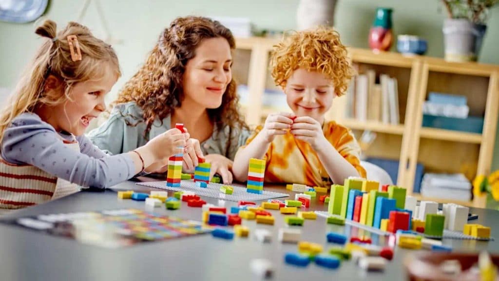 An adult and children playing with their LEGO Braille Bricks