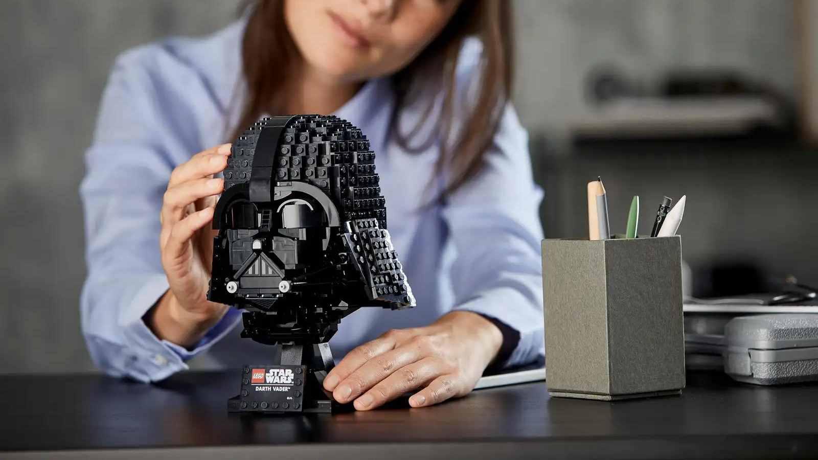 An adult with their LEGO-reimagined Darth Vader Helmet set
