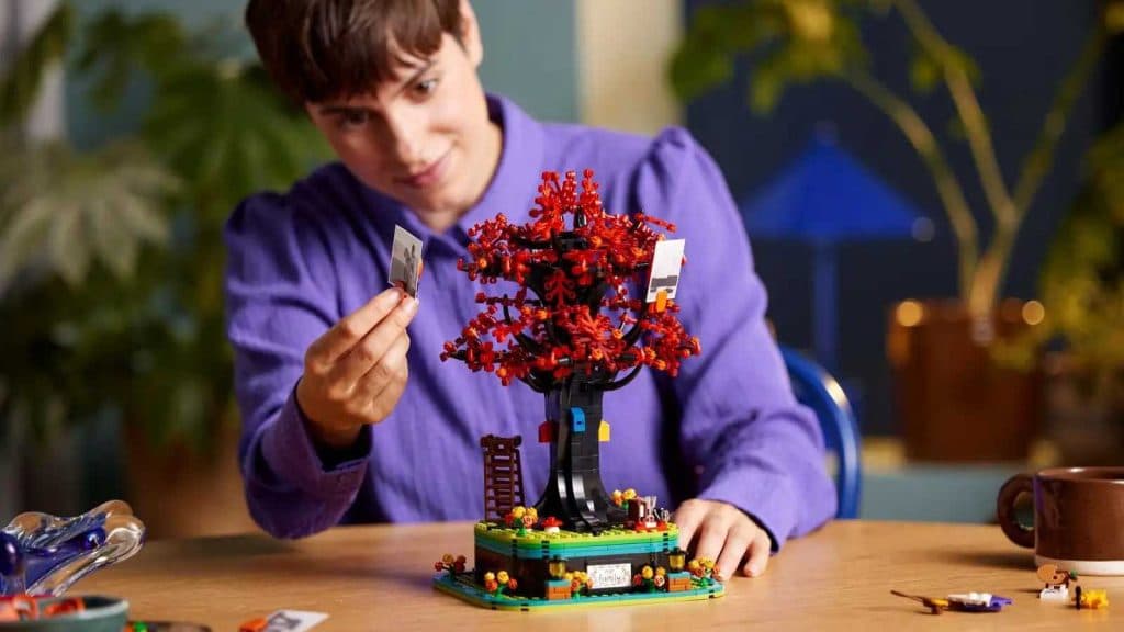 An adult with their LEGO Ideas Family Tree set that will be released in February 2024