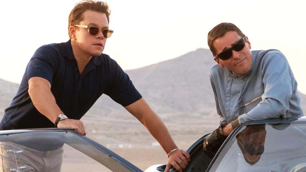 Matt Damon and Christian Bale hang out of a car in Ford V Ferrari
