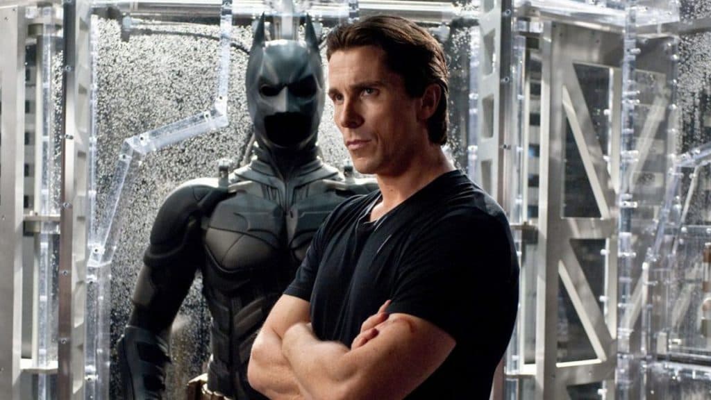 Bruce Wayne (Christian Bale) stands in front of the Bat-Suit.