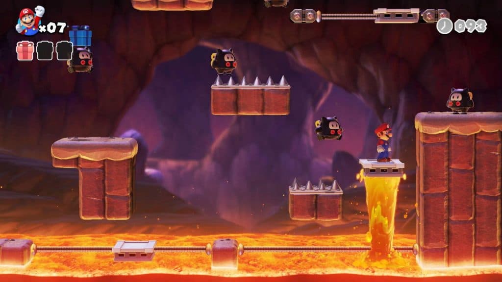 Mario makes his way through a lava level with spikes as obstacles and enemies littered throughout