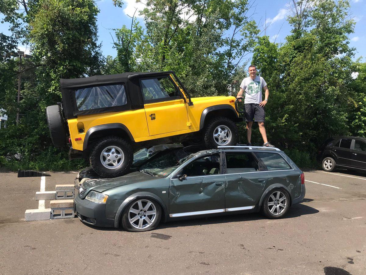 Image of Doug DeMuro with a yellow Land Rover Defender and green Audi.