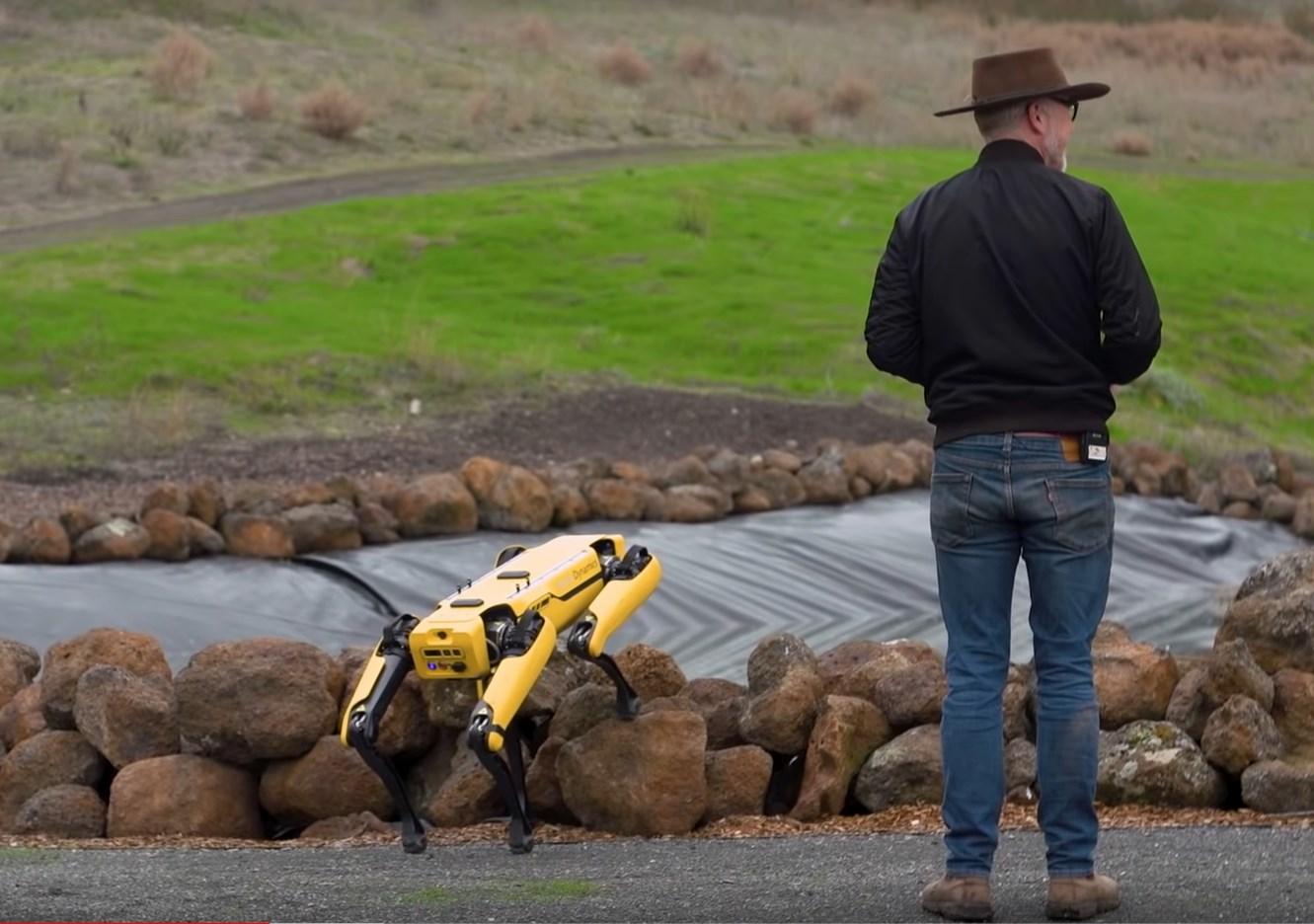 Adam Savage standing outside with the Boston Dynamics robot dog.