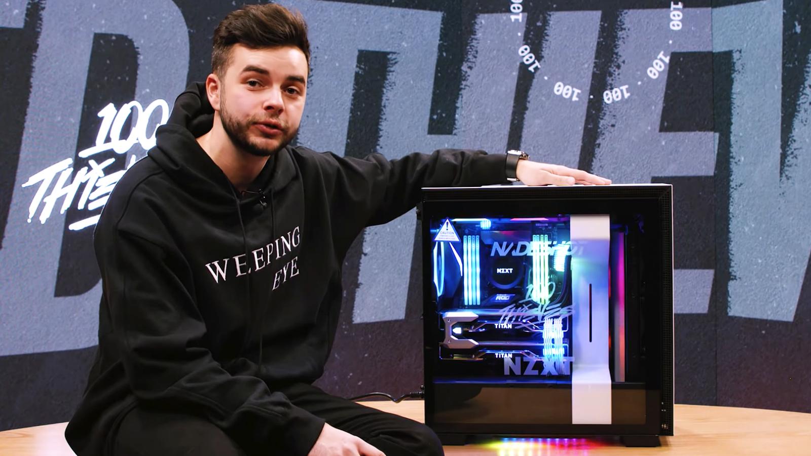 Nadeshot sitting on wooden desk with arm on top of new PC