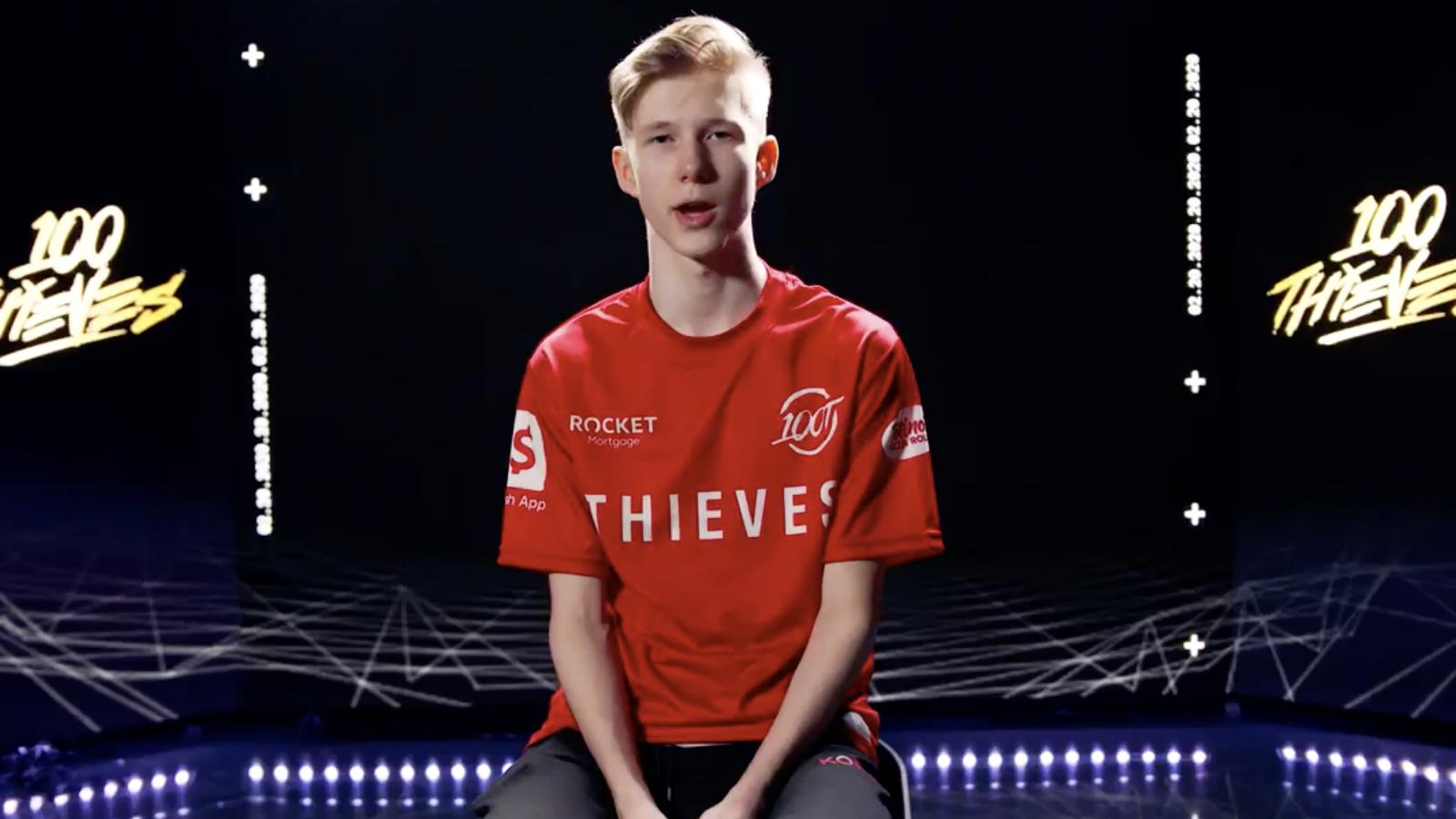 MrSavage in a red 100 Thieves top sitting in a chair