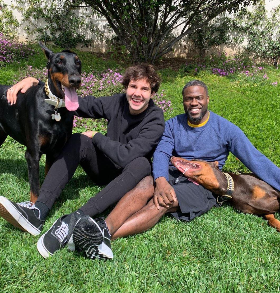 David Dobrik lounges on the grass with Kevin Hart and a dog.