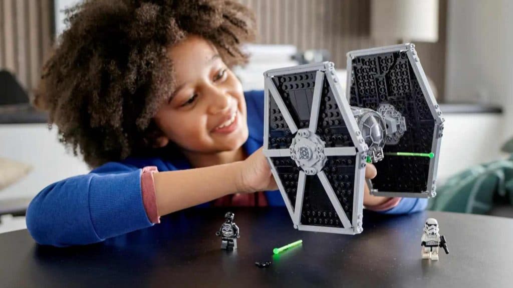 A kid playing with their LEGO-reimagined Imperial TIE Fighter