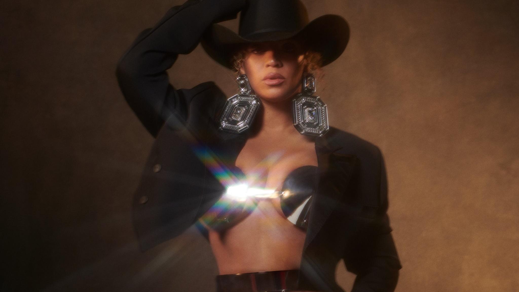 Beyonce in a black cowboy hat standing in front of a brown background