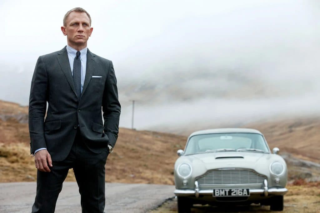 Daniel Craig as James Bond standing outside in front of a car