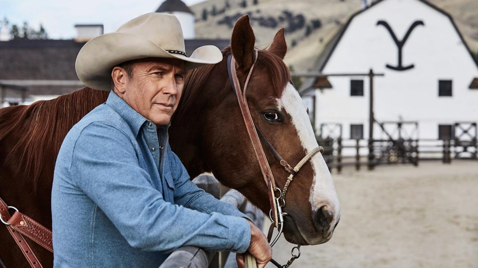 Yellowstone 2024: Kevin Costner as John Dutton in Yellowstone, standing next to a horse outside a barn with the Yellowstone logo
