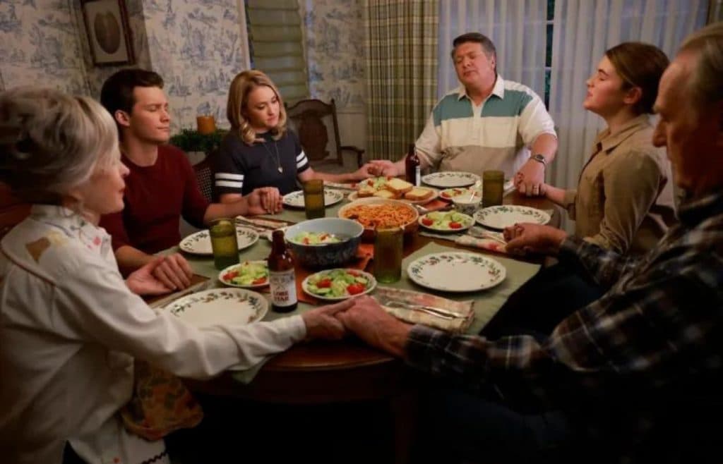 The Cooper family saying Grace at the dining room table in Young Sheldon