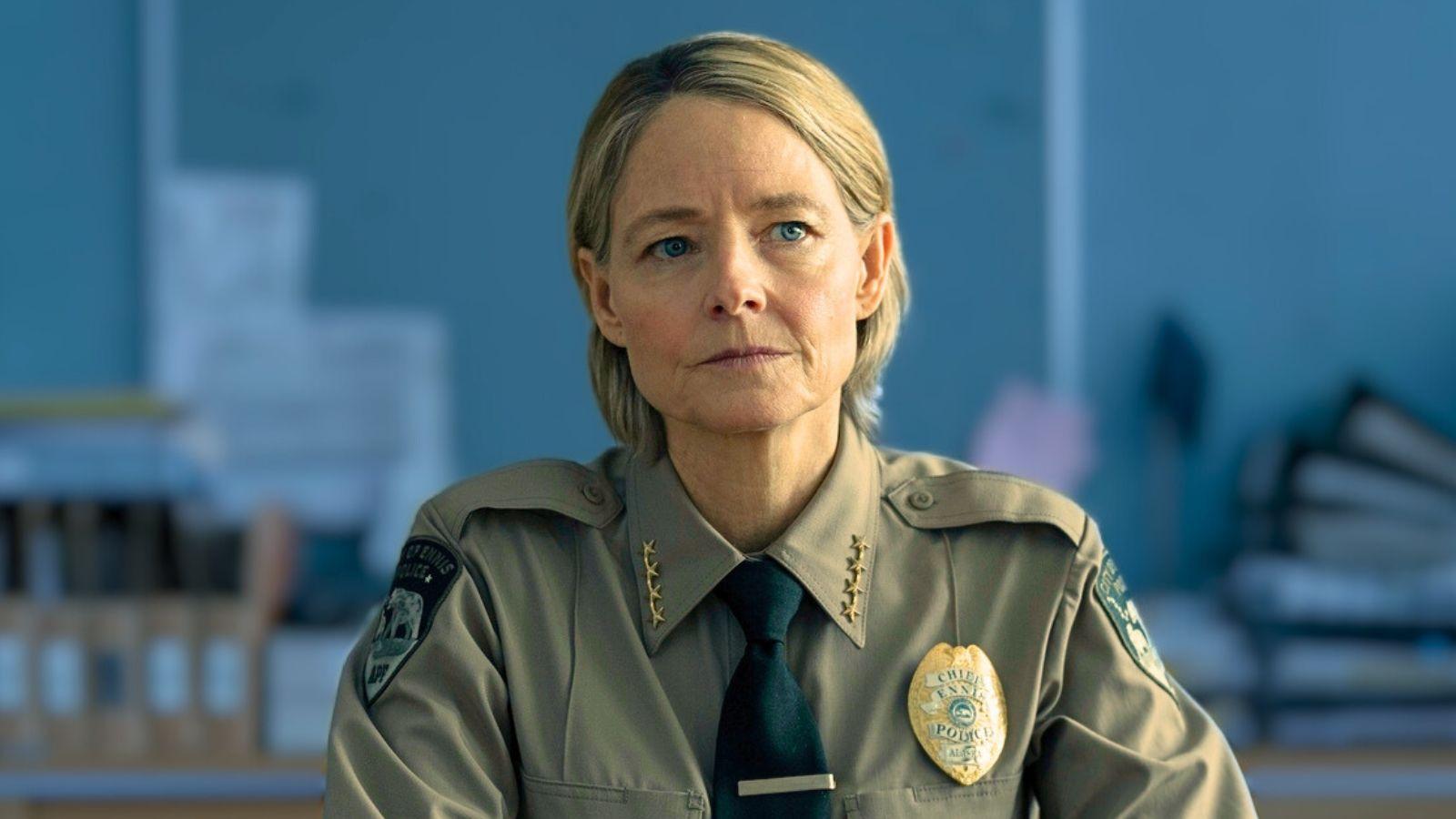 Jodie Foster in True Detective Night Country sits in a police station in her officer uniform.