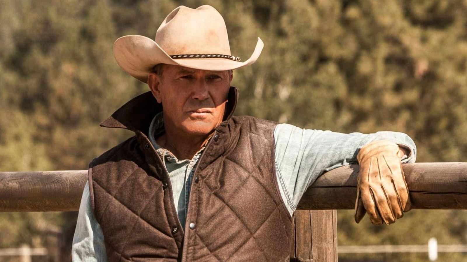 Yellowstone: Kevin Costner as John Dutton, standing outside leaning against a fence
