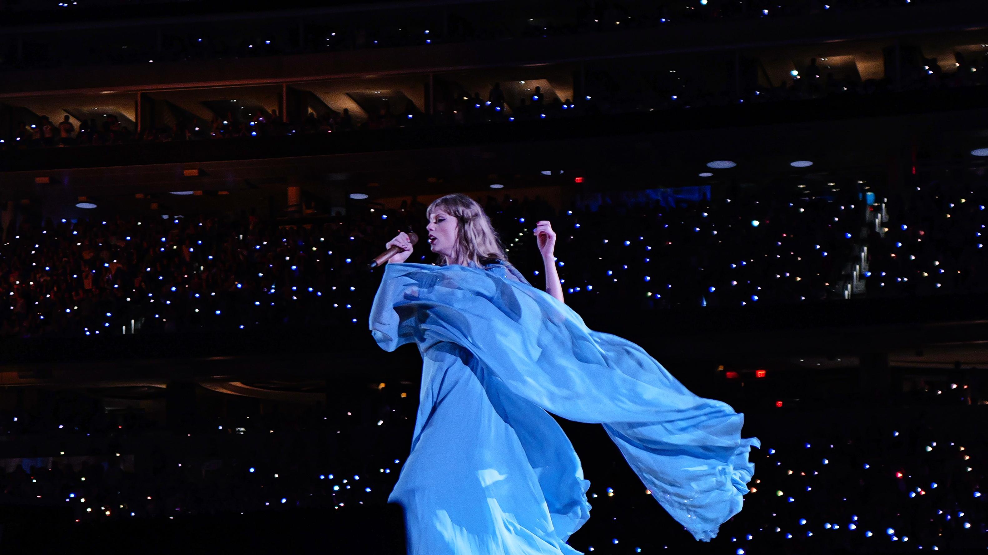 Taylor Swift performing in a blue dress on her Eras Tour