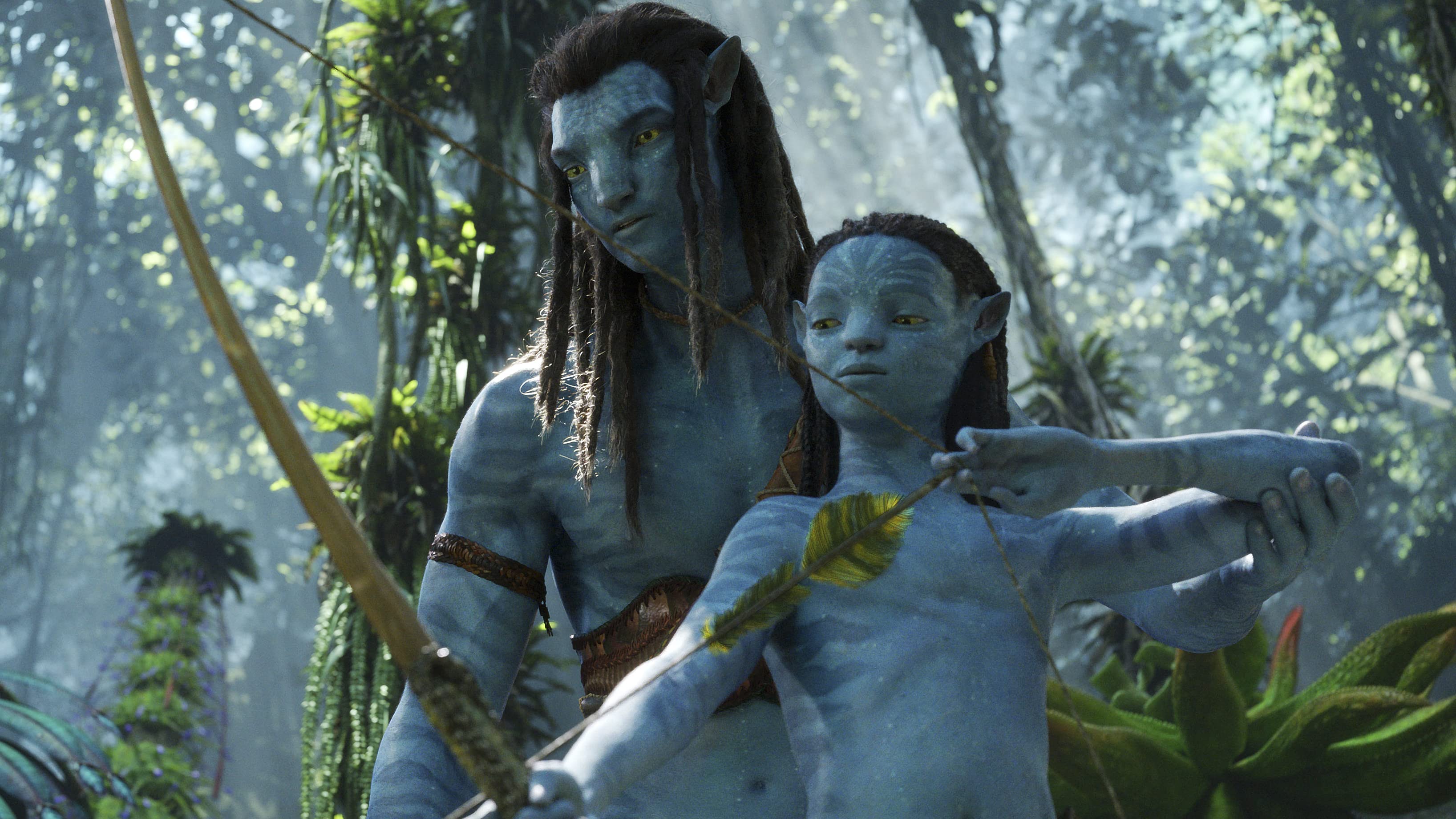 Sam Worthington as Jake Sully in Avatar 2. He is teaching his young son how to shoot a bow.