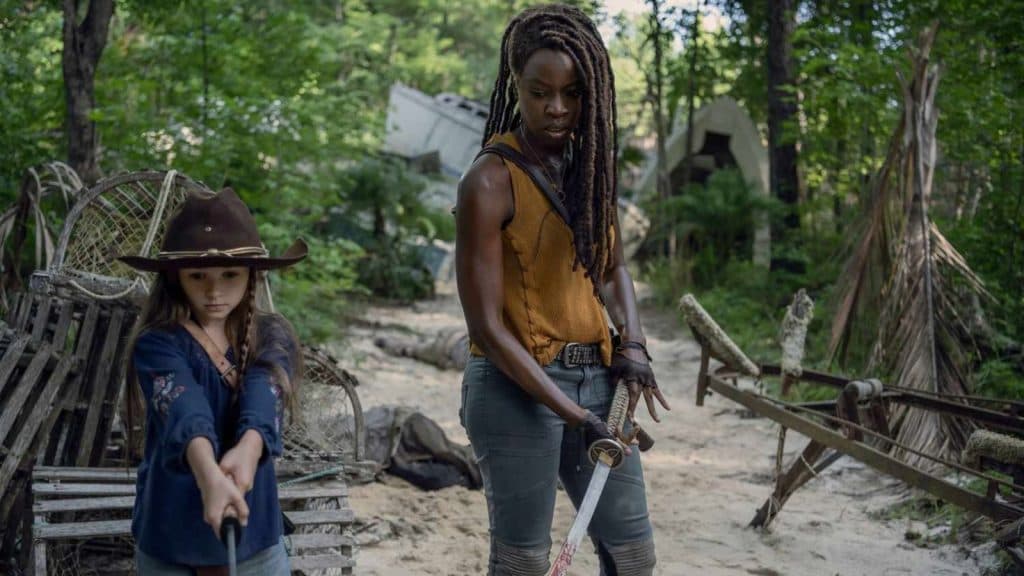The Walking Dead: Michonne and Judith standing in the woods, looking down with their weapons