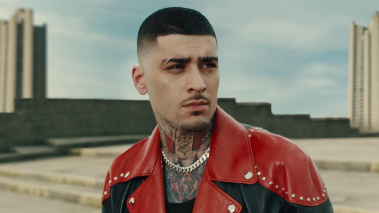Zayn wearing a red and black jacket on a rooftop