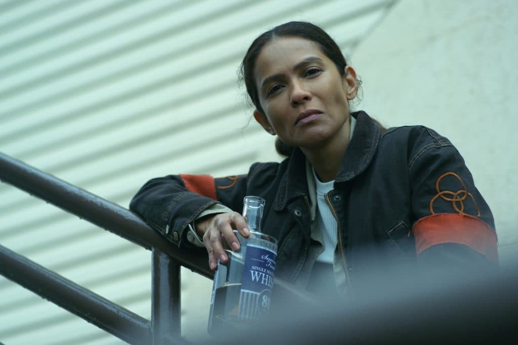 Lesley-Ann Brandt as Thorne in The Walking Dead: The Ones Who Live, sitting on steps and holding a bottle in her hand
