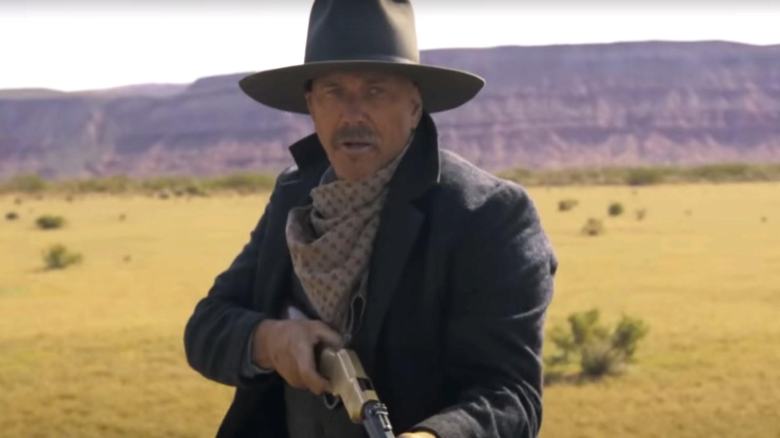 Kevin Costner in Horizon, standing in a field and holding a gun